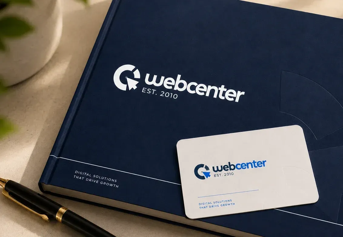 Ein dunkelblaues Notizbuch mit Logo, eine Visitenkarte und ein Stift